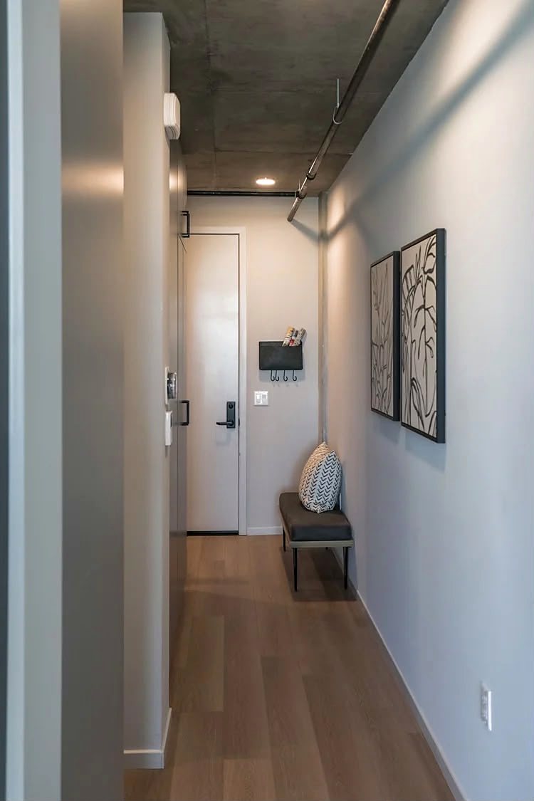 Entry hall with white oak flooring, a bench and framed prints, looking back toward the front door.