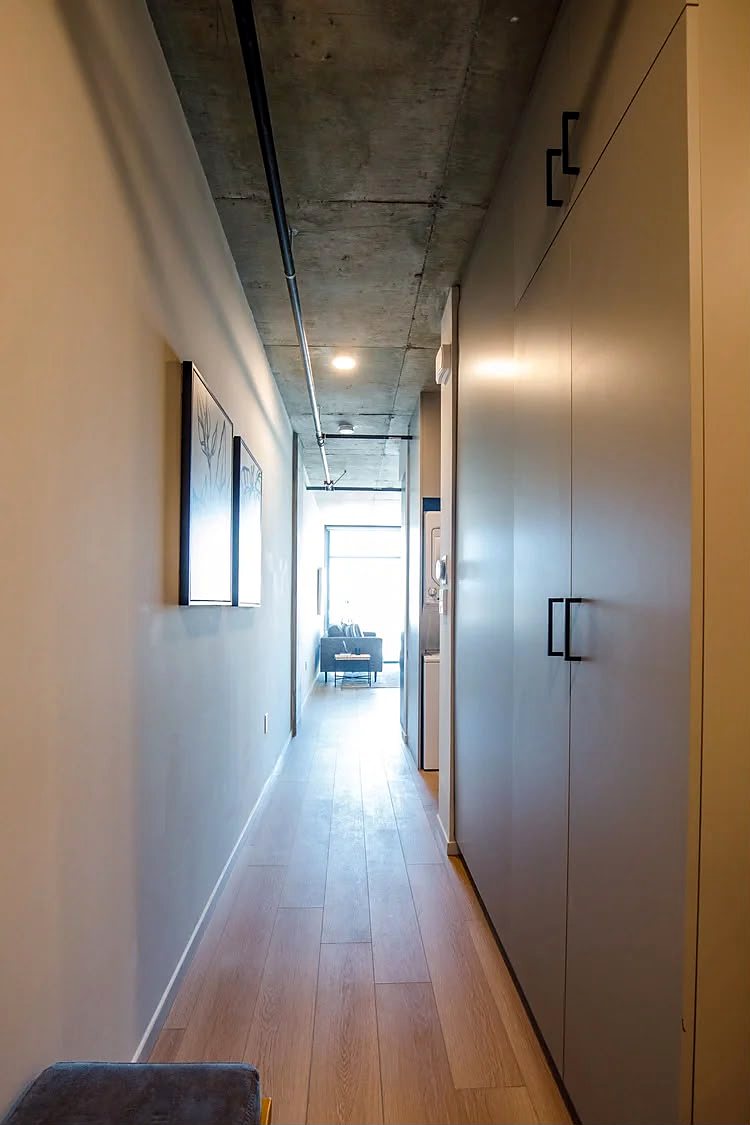 Hallway lined with full-height concealed storage cabinets in a warm neutral finish.