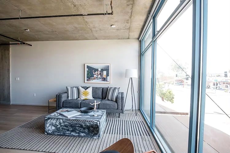 Corner of a living room with a sofa and low table against a two-sided window wall.